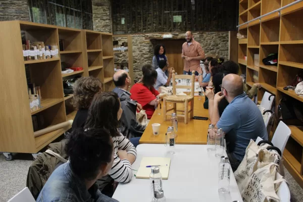 Grupo de persoas participando nun obradoiro sentadas arredor dunha mesa na biblioteca do Pazo de Tor.